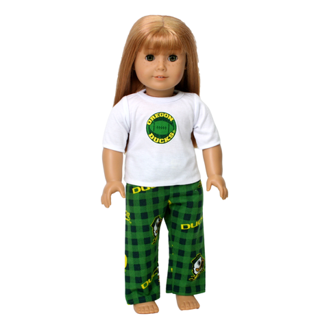 An 18-inch doll wearing a set of Oregon Duck Pajamas, consisting of a white t-shirt with the Oregon Ducks logo and green and yellow flannel pants with the logo.