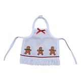Handcrafted gingerbread Christmas apron for 18" dolls with red bow, gingerbread figures, red trim, and white ruffled hem.