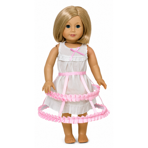 A 18-inch doll wearing a white chemise and a light pink crinoline with a bow detail.