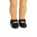 Black Mary Jane dress shoes with pearl-trimmed straps and bow accents shown on the feet of an 18-inch doll.