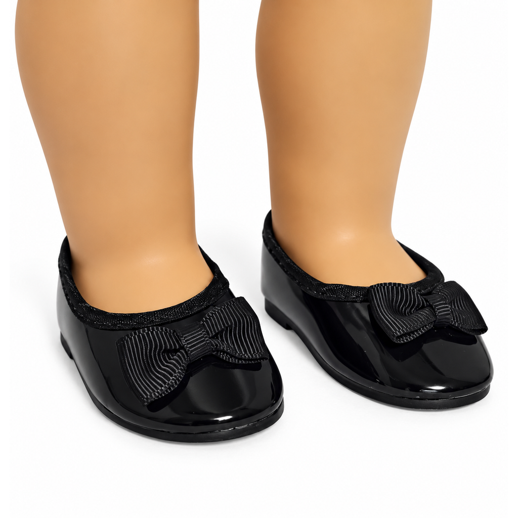 Black patent leather ballet flats with a large textured bow on the front, shown on an 18-inch doll's legs against a white background.