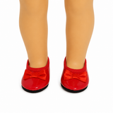 A pair of bright red patent leather shoes with matching red satin bow details, shown on an 18-inch doll's legs against a plain white background.