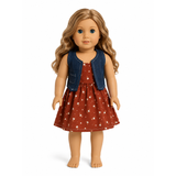 An 18-inch doll with long wavy light brown hair wearing a rust red dress with white polka dots and a blue denim vest, standing against a plain white background.