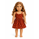 An 18-inch doll with long wavy light brown hair wearing a rust-red sleeveless dress with a small white floral pattern, standing against a plain white background.